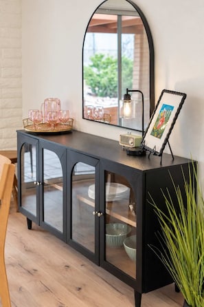 A black console table with a mirror, a picture frame, and a vintage lamp.