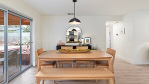 A dining area with a wooden table, benches, and a black pendant light. - Uptown Red Rock Retreat | Hot Tub & Patio Views (Sedona)