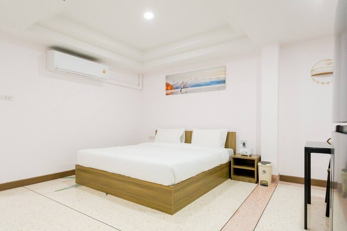 A bedroom with a bed, bedside table, and a wall-mounted air conditioner.