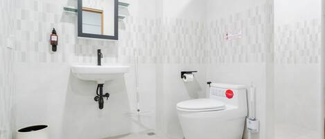 A modern bathroom with a white sink, mirror, and toilet.