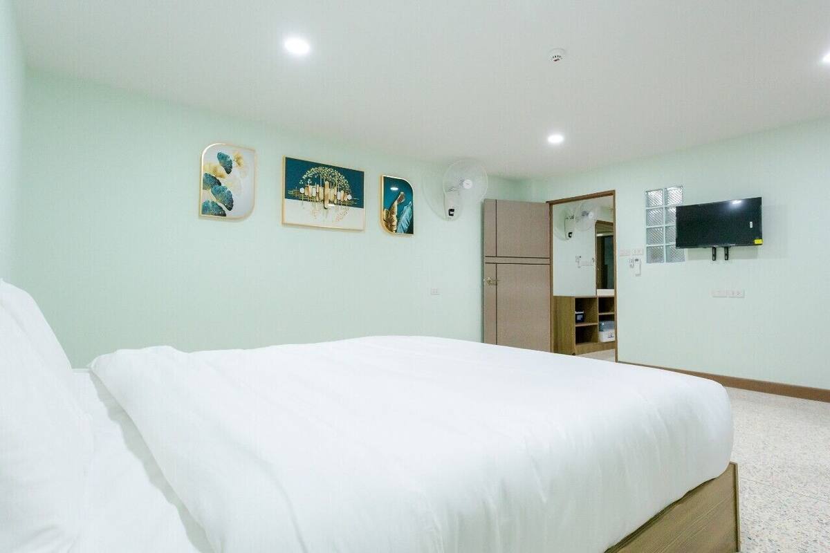 A hotel room with a bed, a wardrobe, a TV, and artwork on the wall.