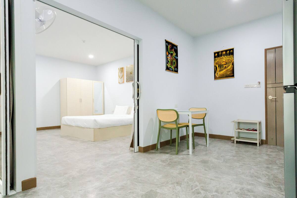 A hotel room with a bed, a chair, a small table, and two wall-mounted artworks.