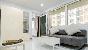 A modern living room with a grey sofa, white coffee table, and a wardrobe. - Rama Residency Sukhumvit Bangkok (Bangkok)