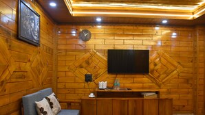 Un interno in legno con un divano, un tavolino da caffè, una TV a parete e una sveglia.