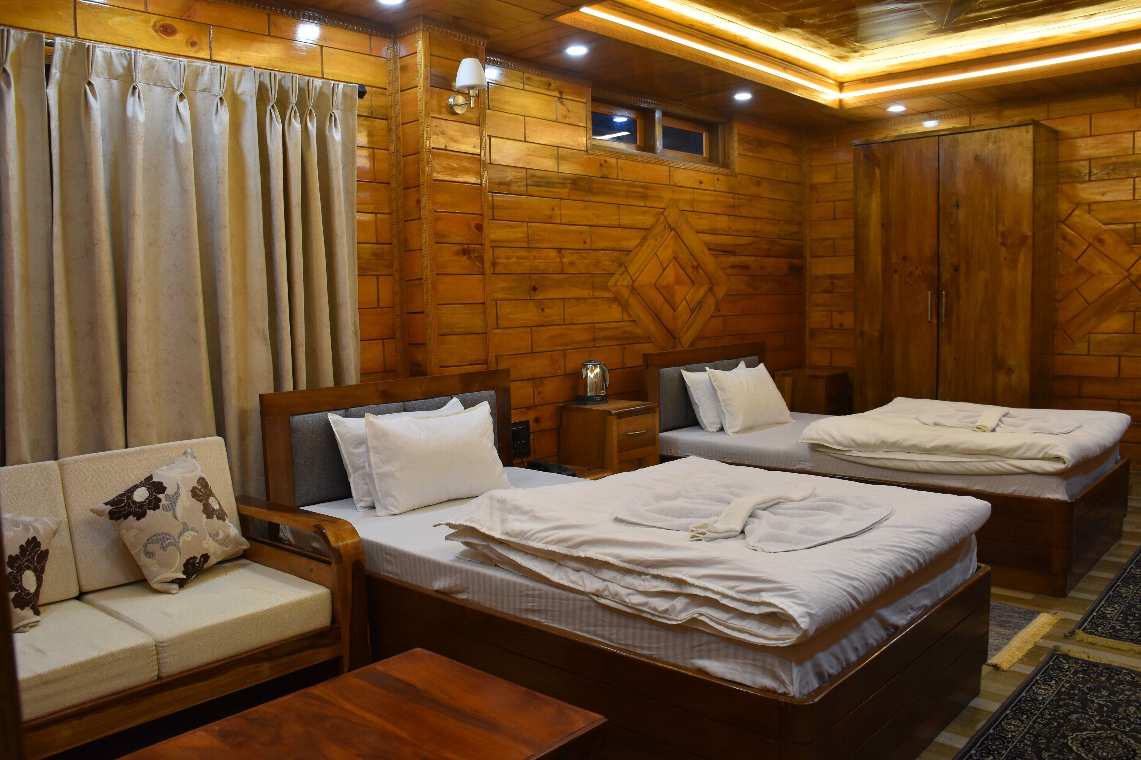 A wooden cabin-style room with two beds, a sofa, and a small table.