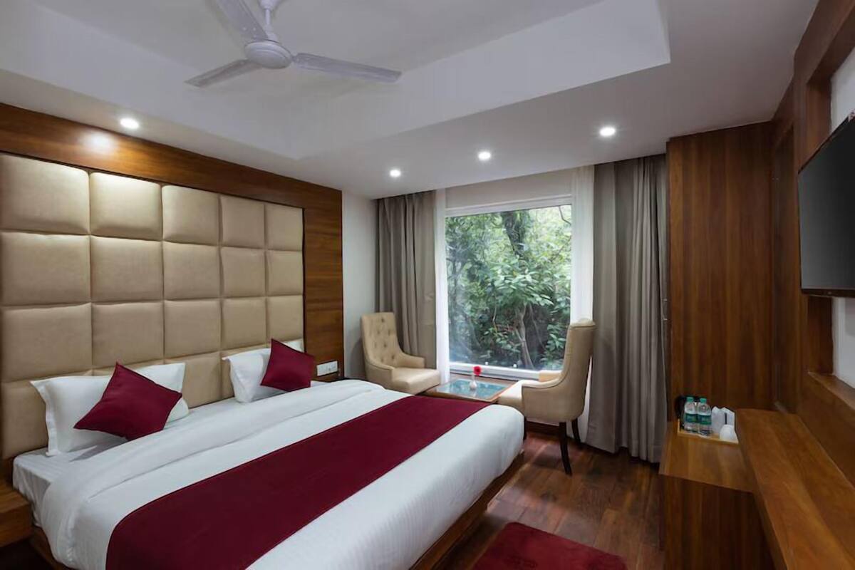A modern hotel room with a large bed, a desk, a chair, and a TV.