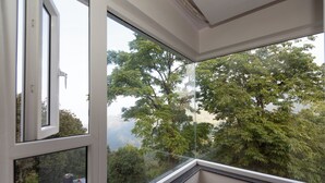 Una habitación con un ventanal, vistas a árboles y una esquina con piso de madera.