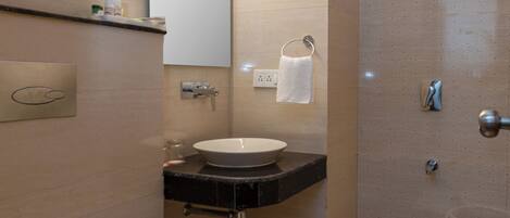 A modern bathroom with a toilet, sink, mirror, shower, and wooden flooring.
