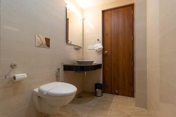 Un baño pequeño con inodoro, lavamanos, espejo y una puerta de madera.