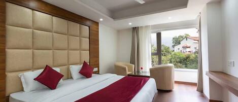 Een moderne hotelkamer met een groot bed, een plafondventilator en uitzicht op de omgeving.