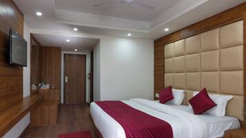 A hotel room with a bed, a TV, a ceiling fan, and wooden paneling.