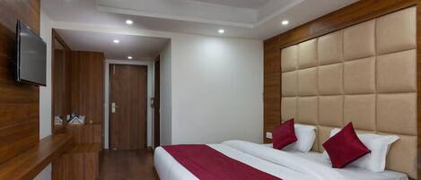 Una habitación de hotel con una cama grande, un cabecero de madera, un televisor montado en la pared y un ventilador de techo.