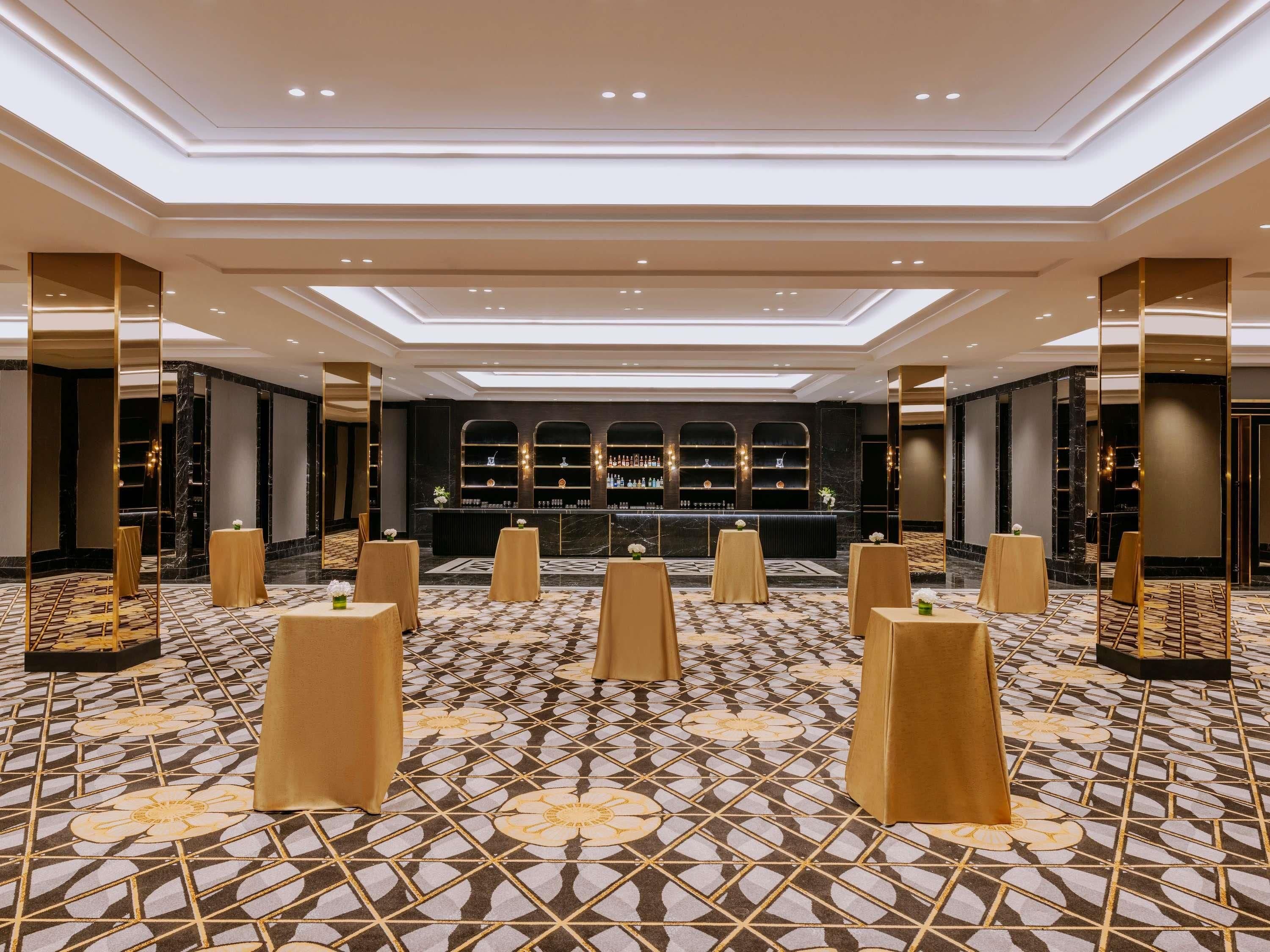 A hotel lobby with a bar area, patterned floor, and modern lighting.