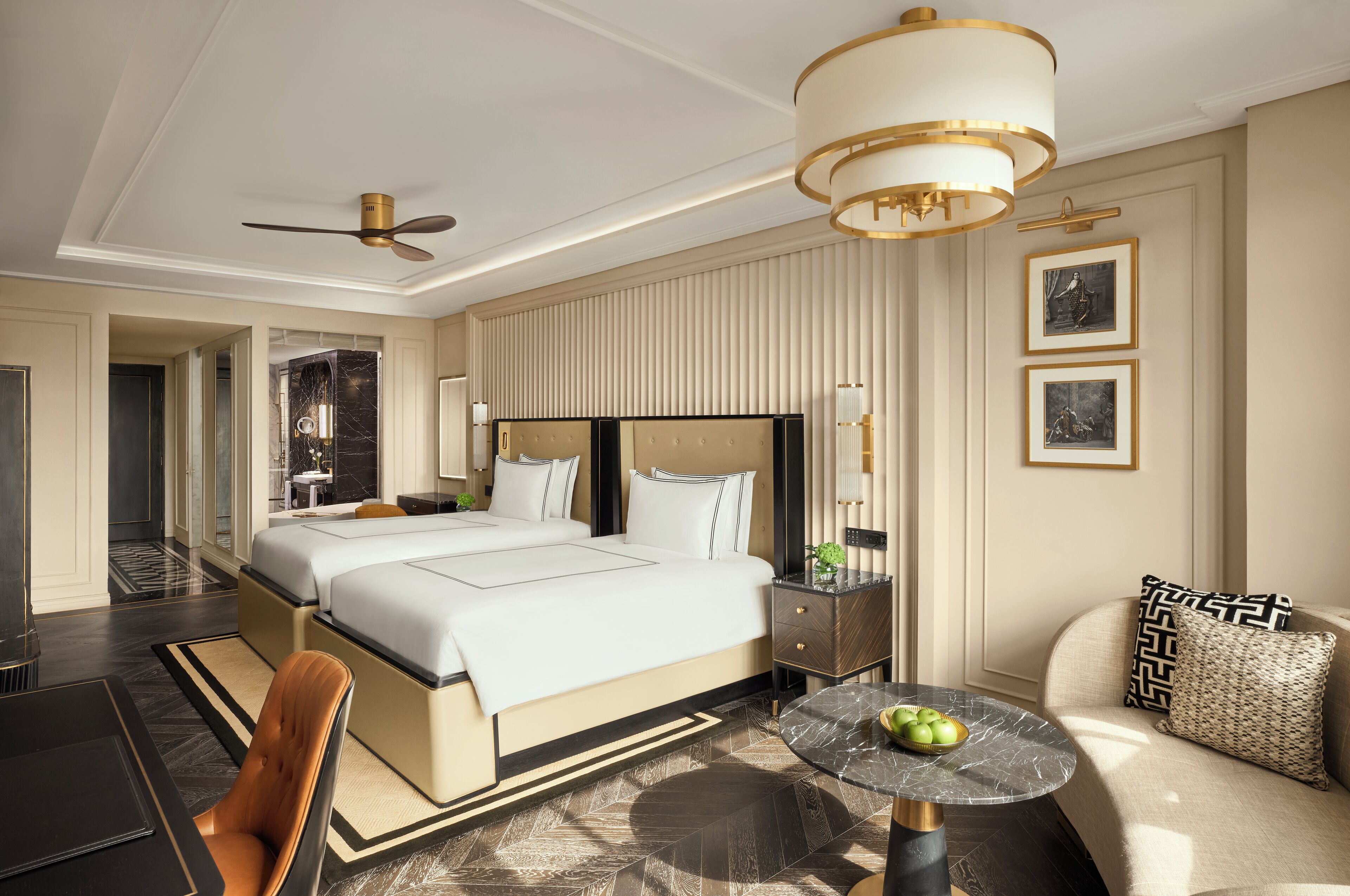 A modern hotel room with a large bed, a sitting area with a table, and a ceiling fan.