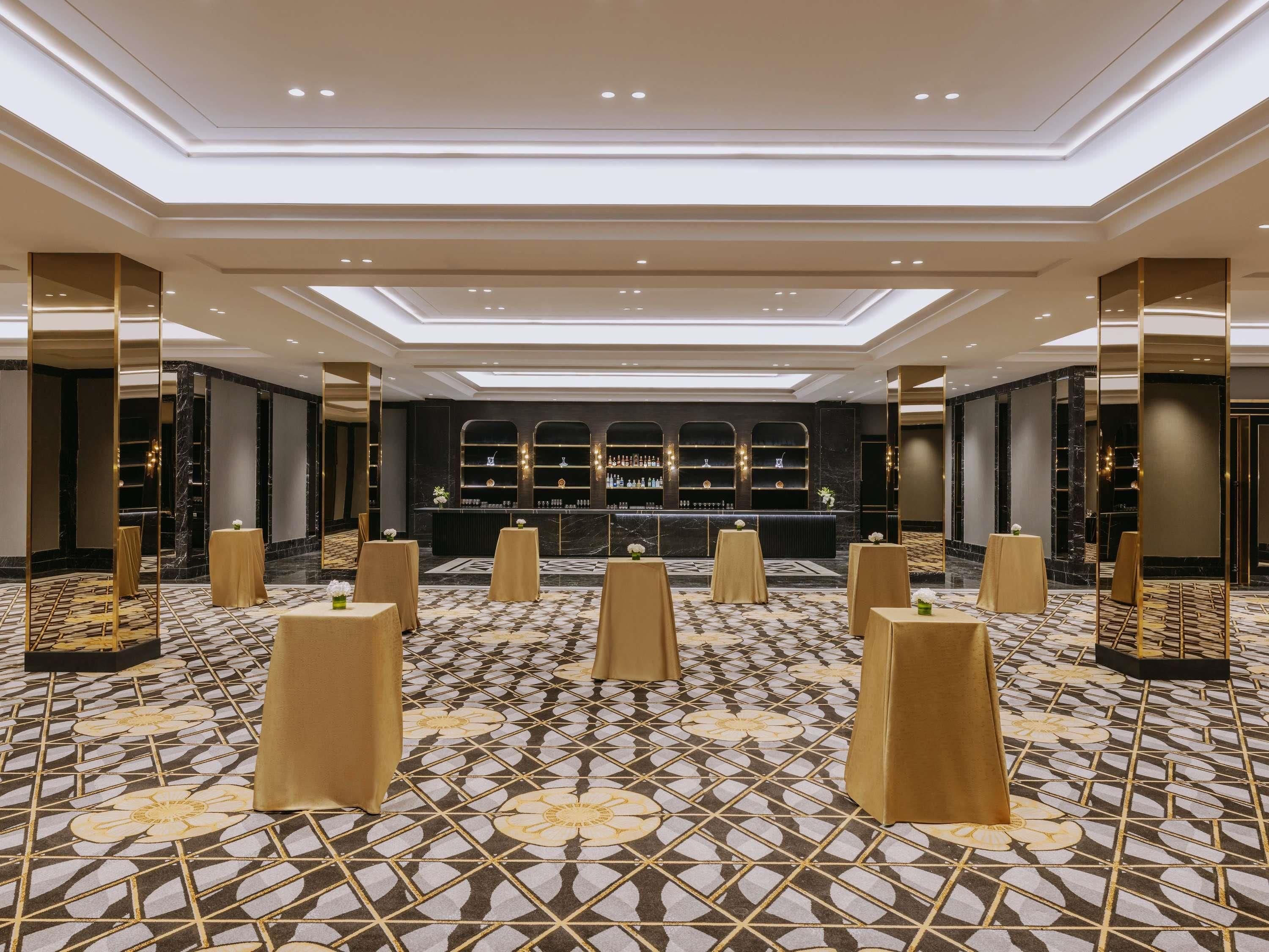 Un hall de hotel con zona de bar, suelo estampado e iluminación moderna.