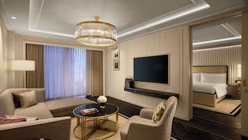 Et hotelværelse med sofa, lænestol, rundt sofabord, fjernsyn og en seng.