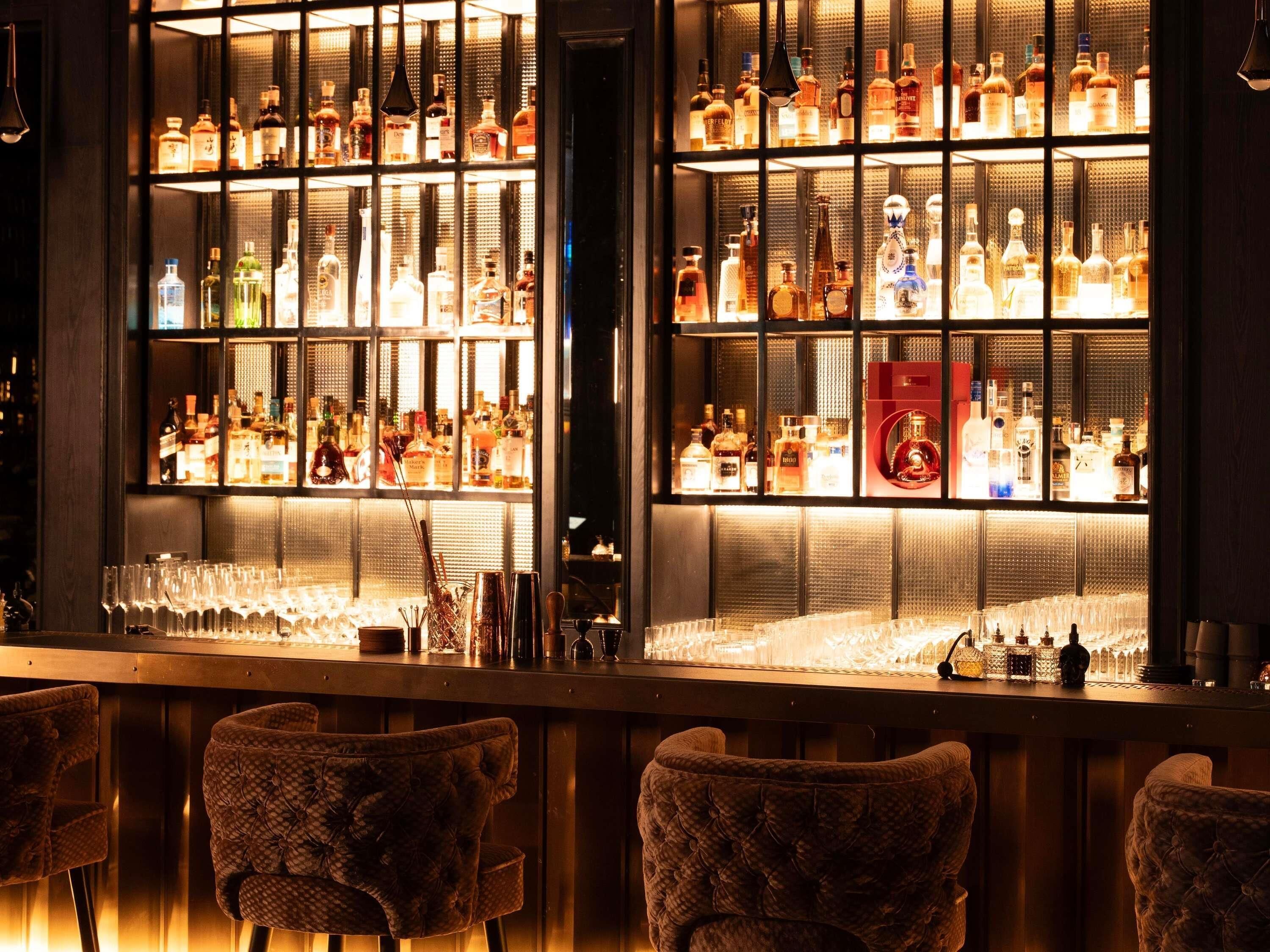 Un bar con estantes llenos de botellas de licores, vasos y utensilios.