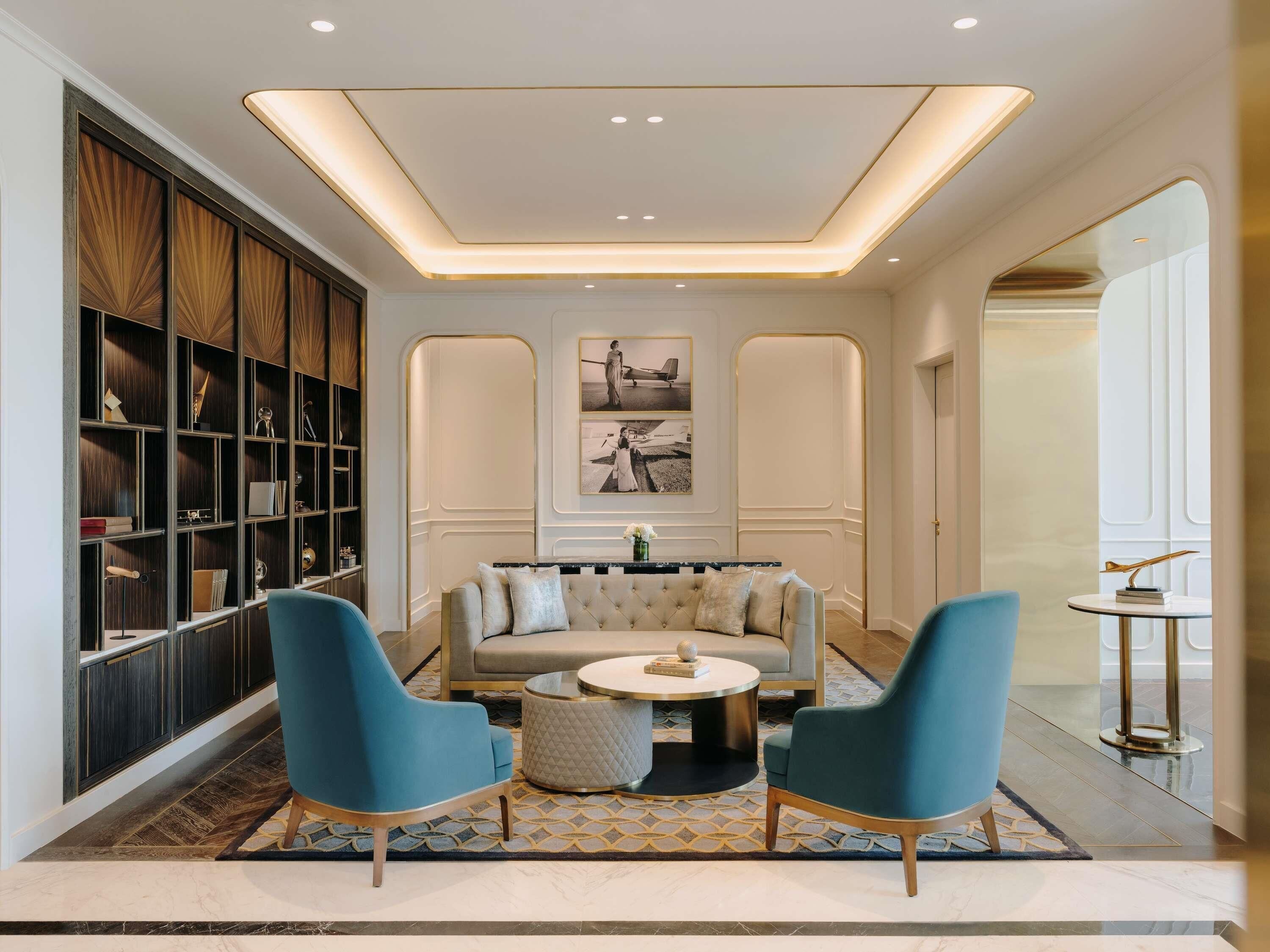 A modern living room with a sofa, two armchairs, a coffee table, and a bookshelf.