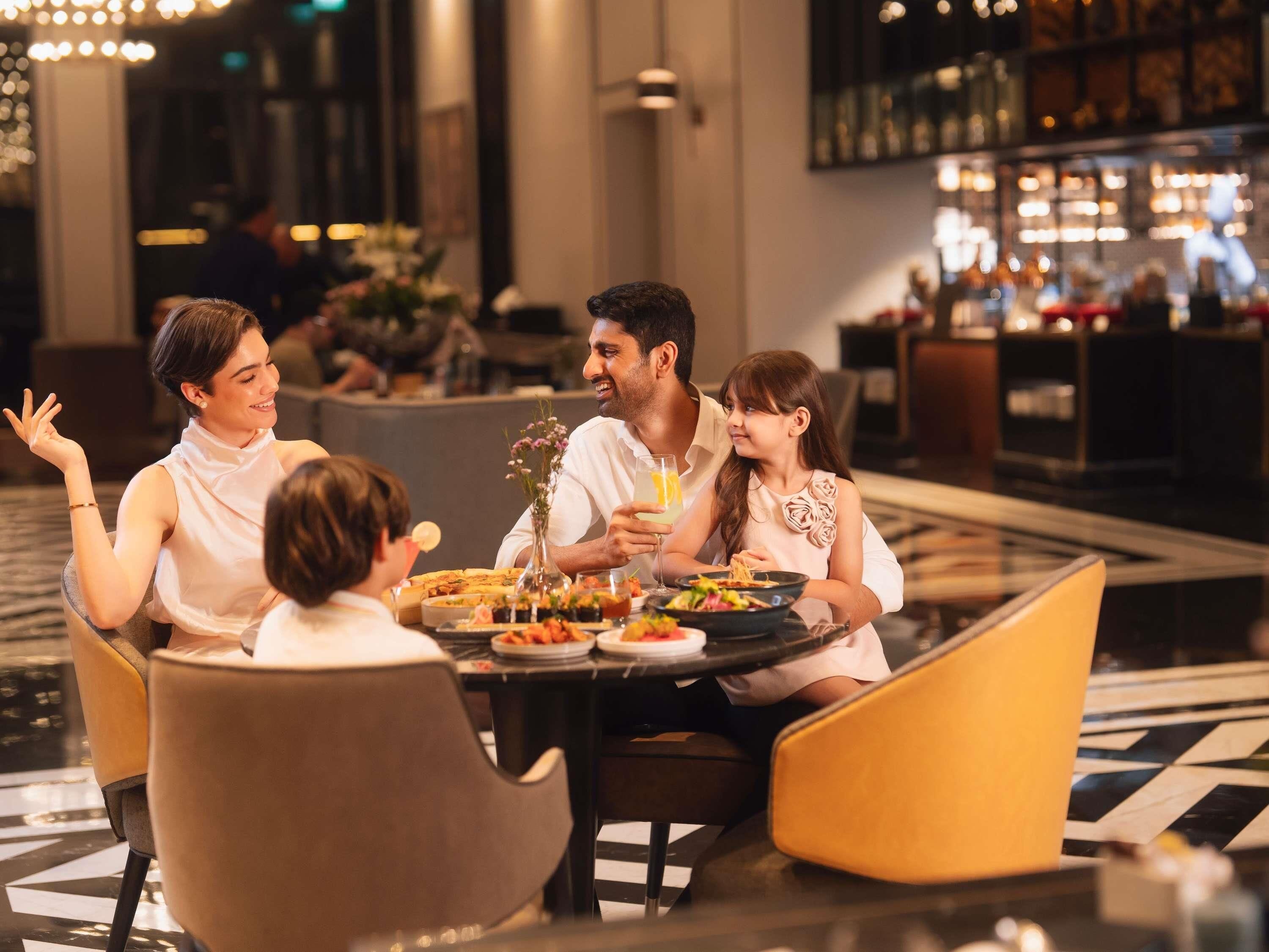 A family dining at a hotel restaurant with a bar in the background.