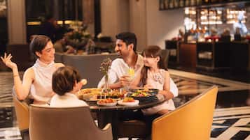 A family dining at a hotel restaurant with a bar in the background.