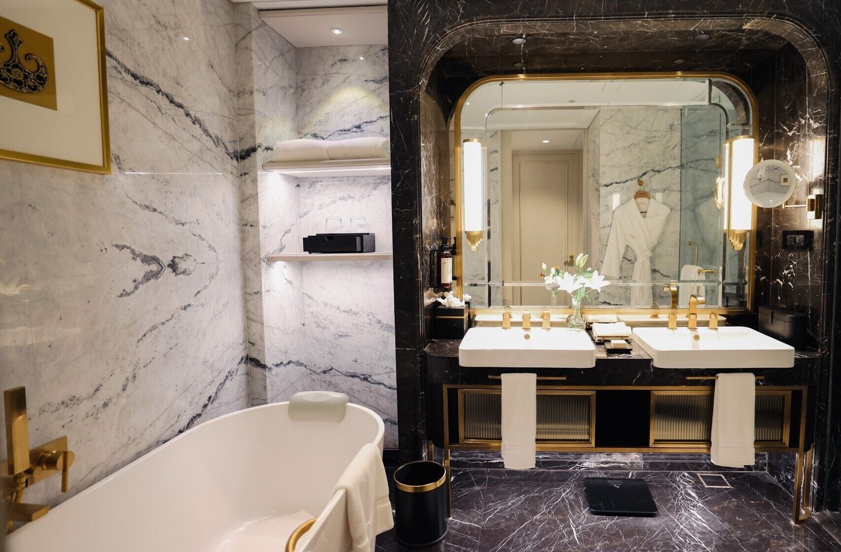 A luxurious bathroom with a large bathtub, two sinks, and a mirror with a gold frame.