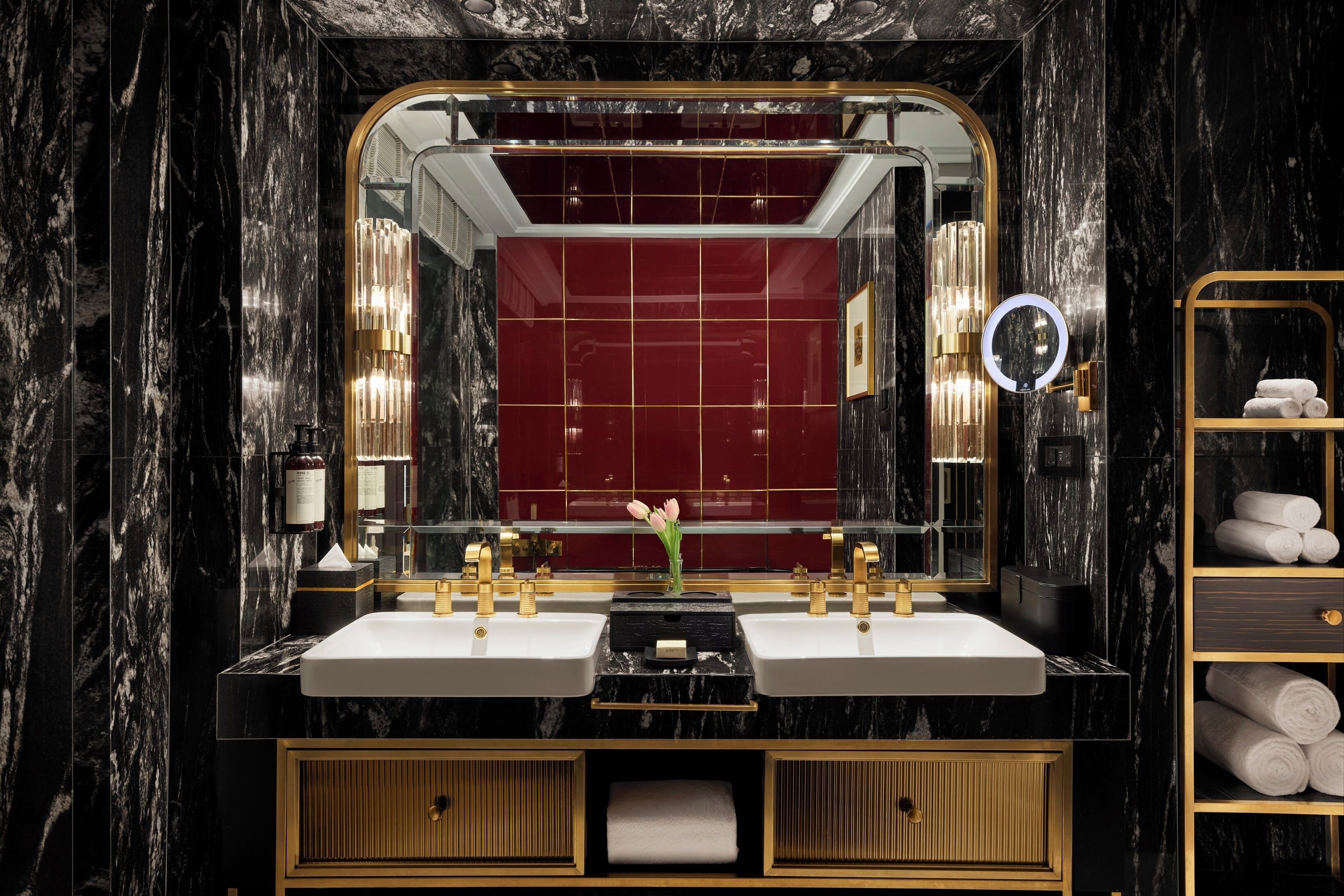A luxurious bathroom with two sinks, a large mirror, and a vanity with a gold frame.