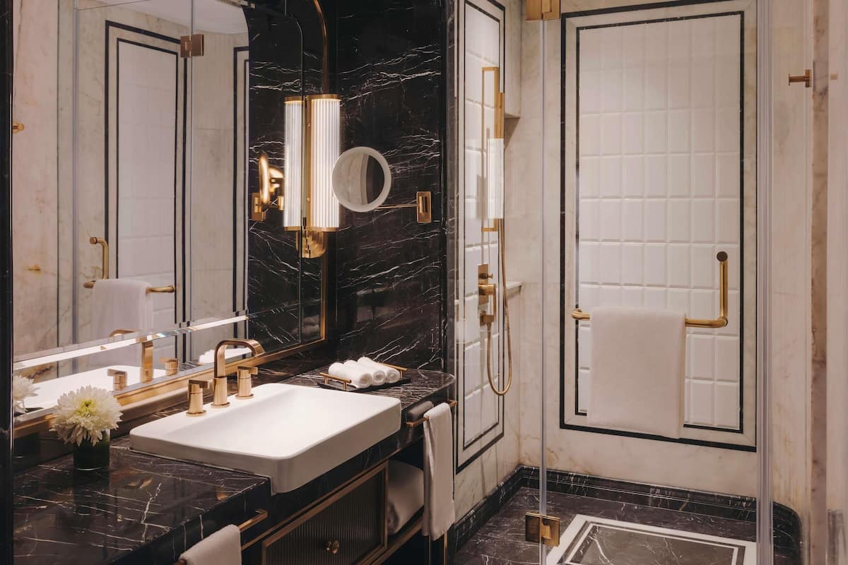A modern bathroom with a large mirror, a sink, a shower, and a toilet.