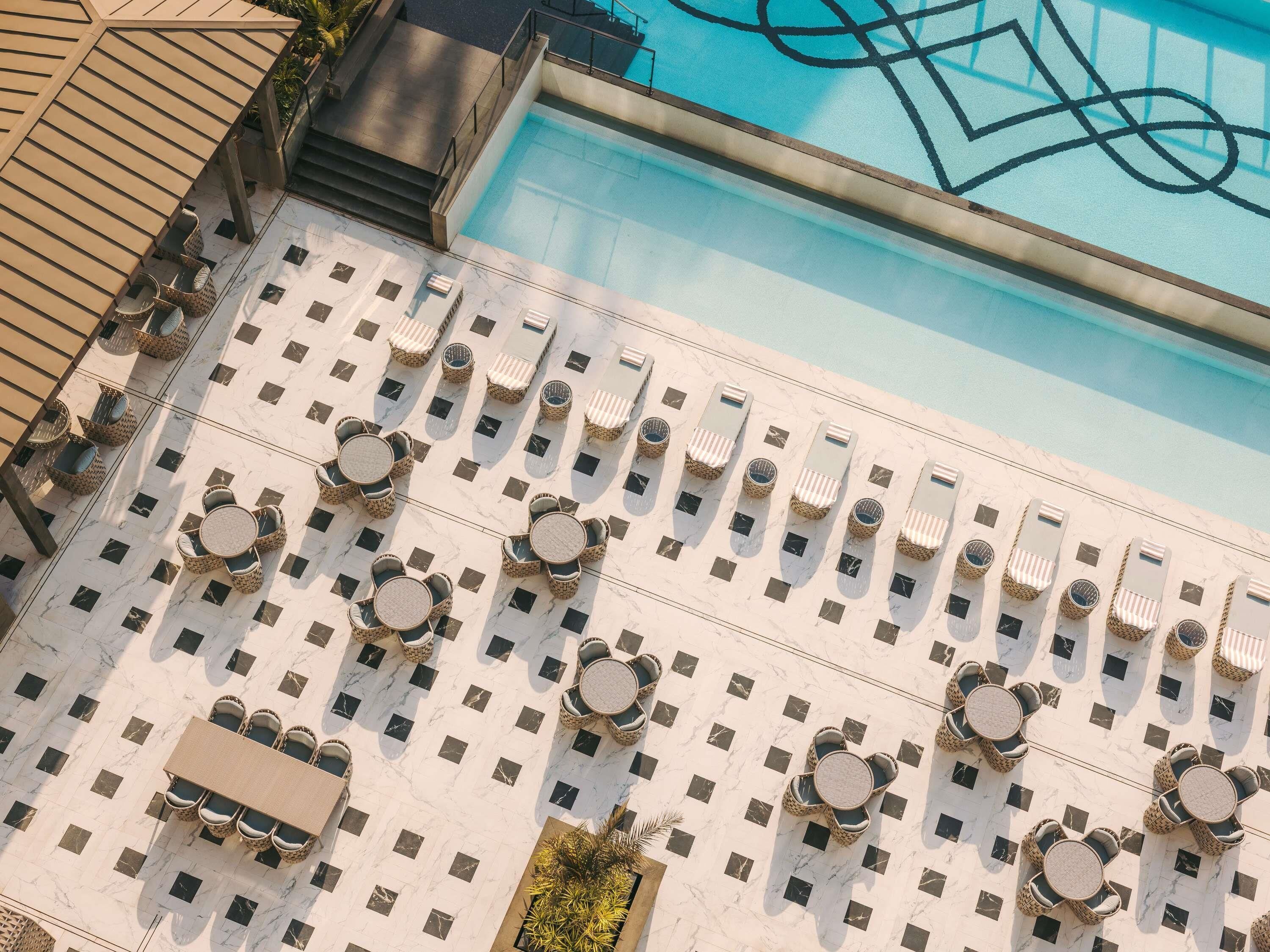 A rooftop pool area with multiple lounge chairs and tables arranged in a grid pattern.