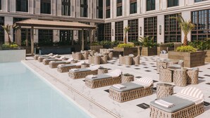 Un área de piscina en la azotea con sillones de mimbre y una zona de estar cubierta.