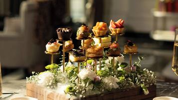 A dessert display with various pastries on stands, surrounded by white flowers and a wooden box.