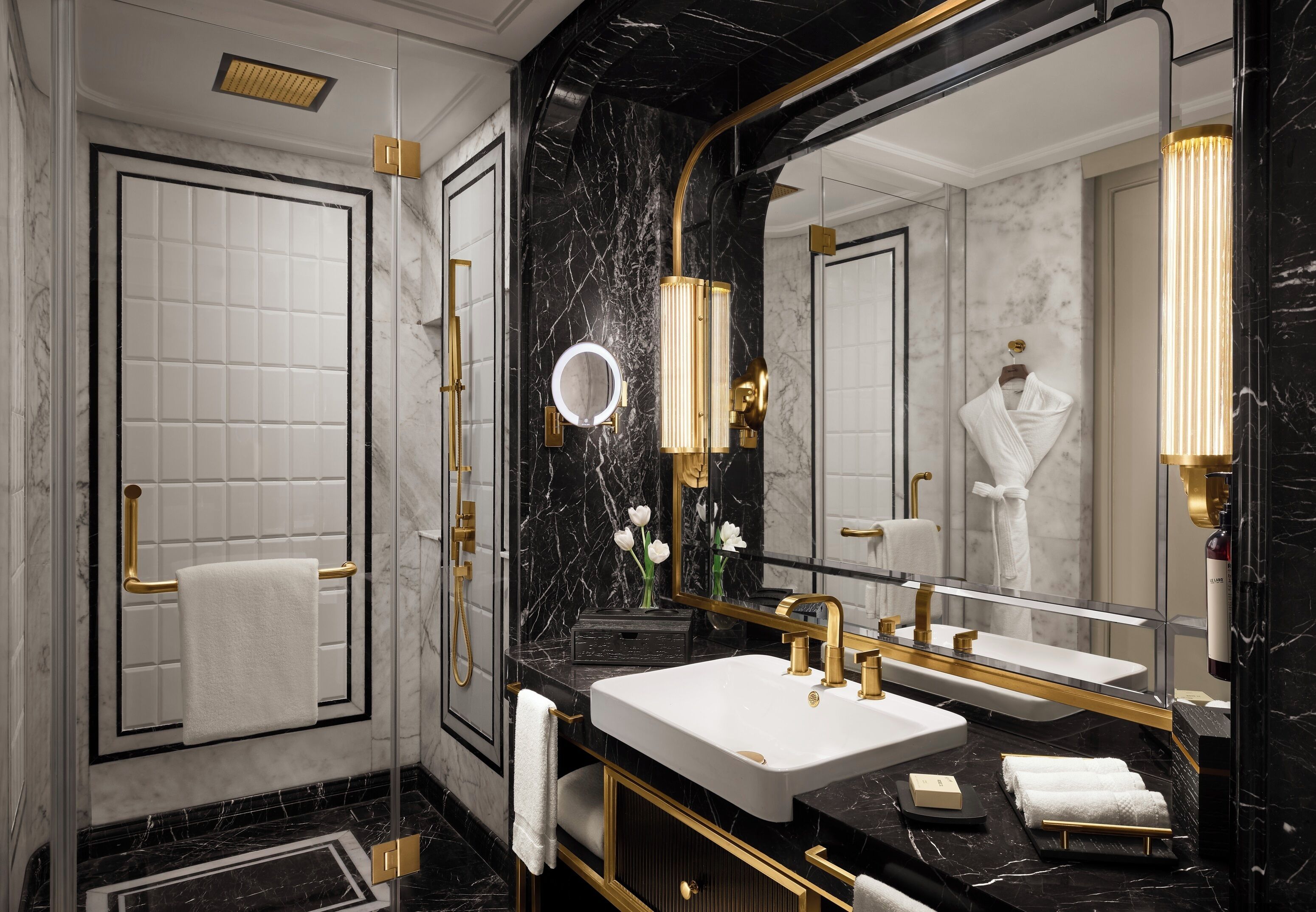 A luxurious bathroom with a large mirror, two sinks, and a towel rack.