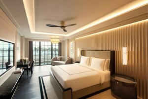Una habitación de hotel moderna con una cama grande, un escritorio y una silla. Hay un ventilador de techo y una ventana con vistas al exterior.