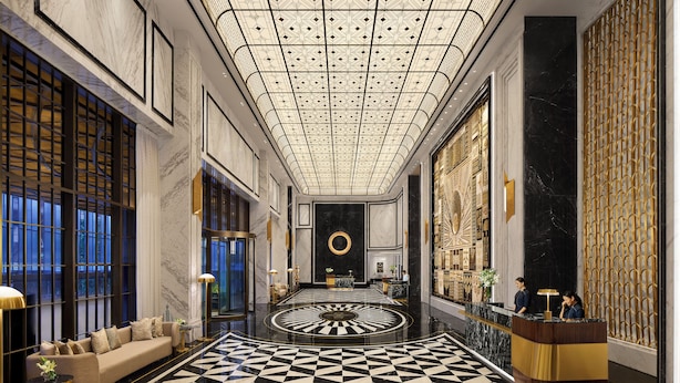 Un lobby lujoso con un patrón geométrico en el suelo de blanco y negro, un diseño circular central y un mostrador de recepción con dos empleados.