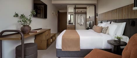 A modern hotel room with a large bed, a desk, a chair, and a small round table.