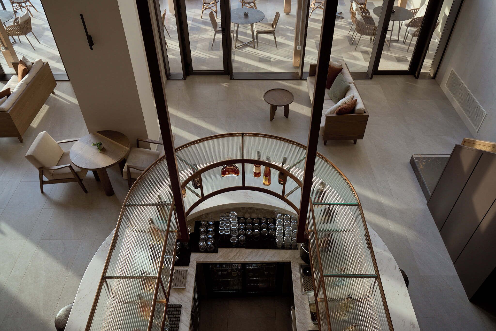 A modern interior with a central staircase, seating areas, and a glass railing.