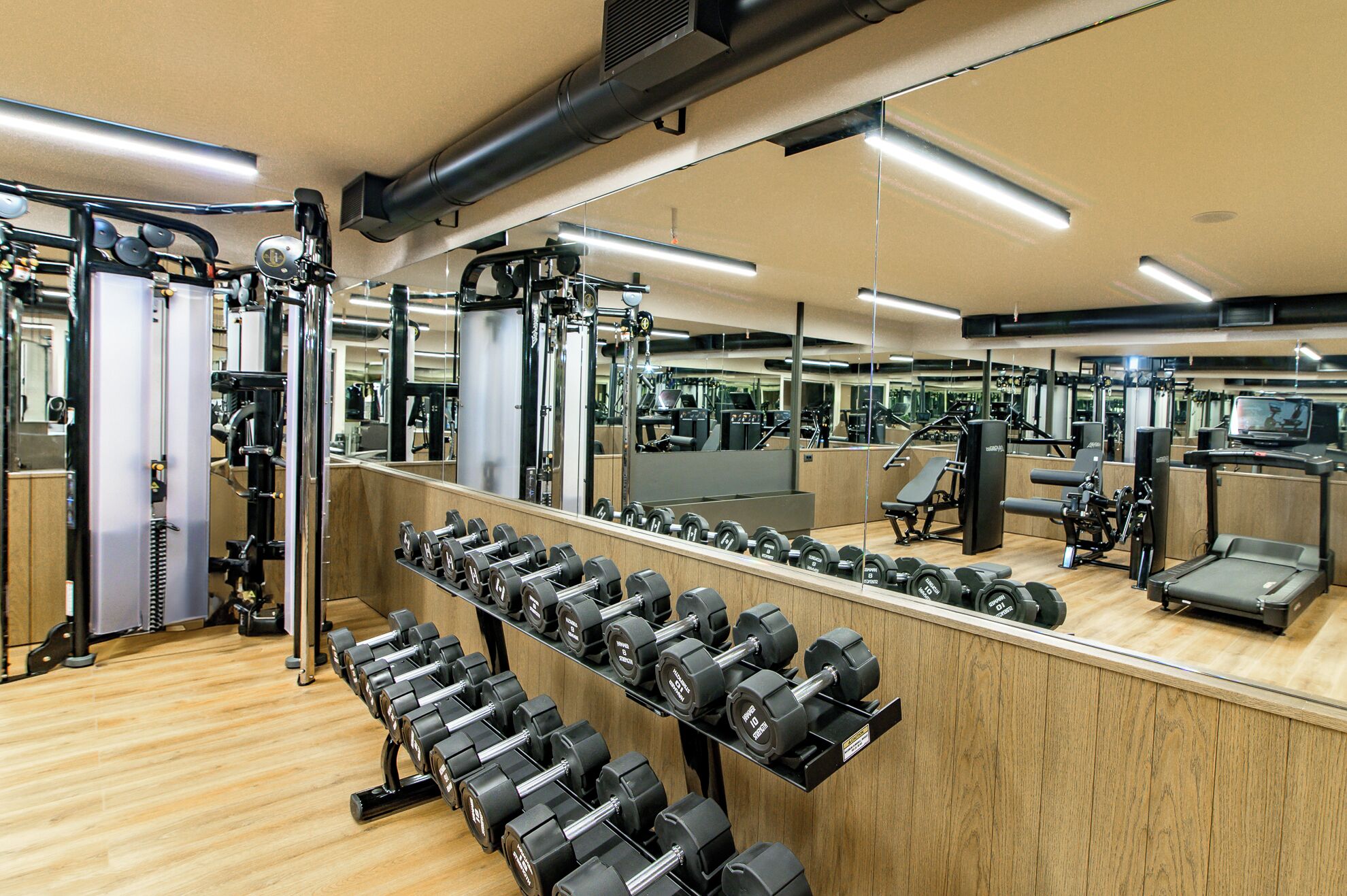 Een sportschool met diverse fitnessapparaten, waaronder gewichten en loopbanden.
