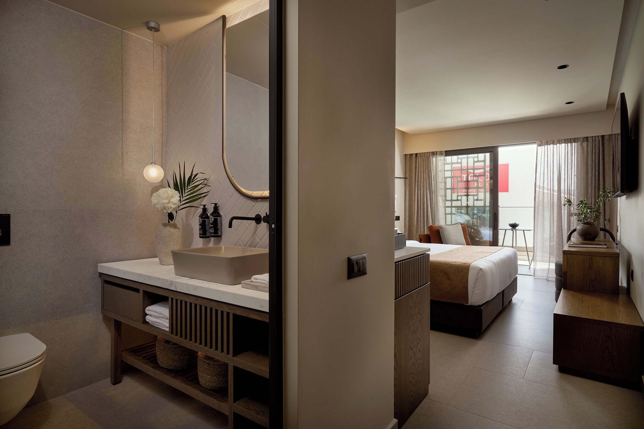 A modern bathroom with a large mirror, a sink, and a toilet.