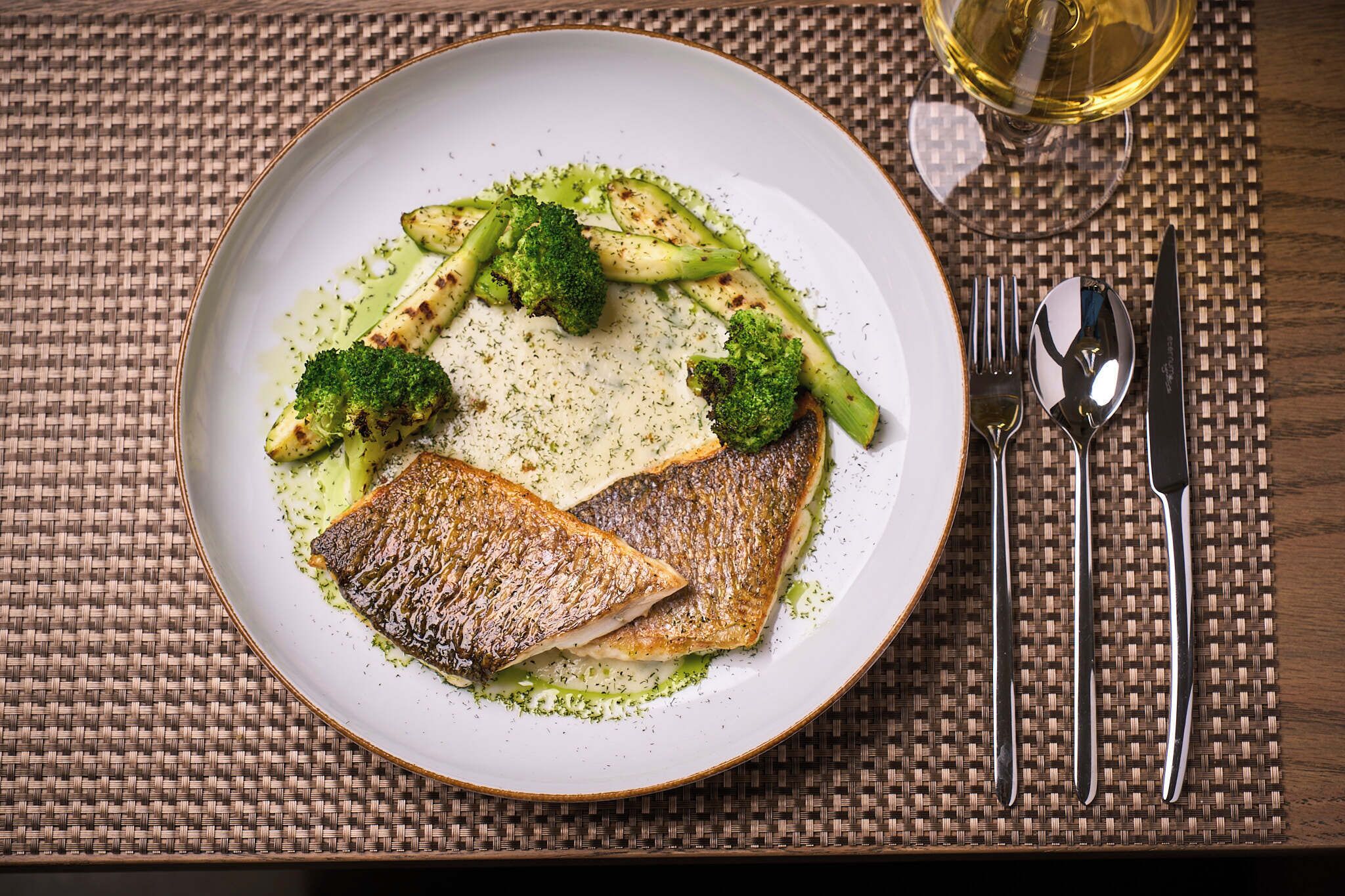 A plate of food with fish and vegetables on a woven placemat.