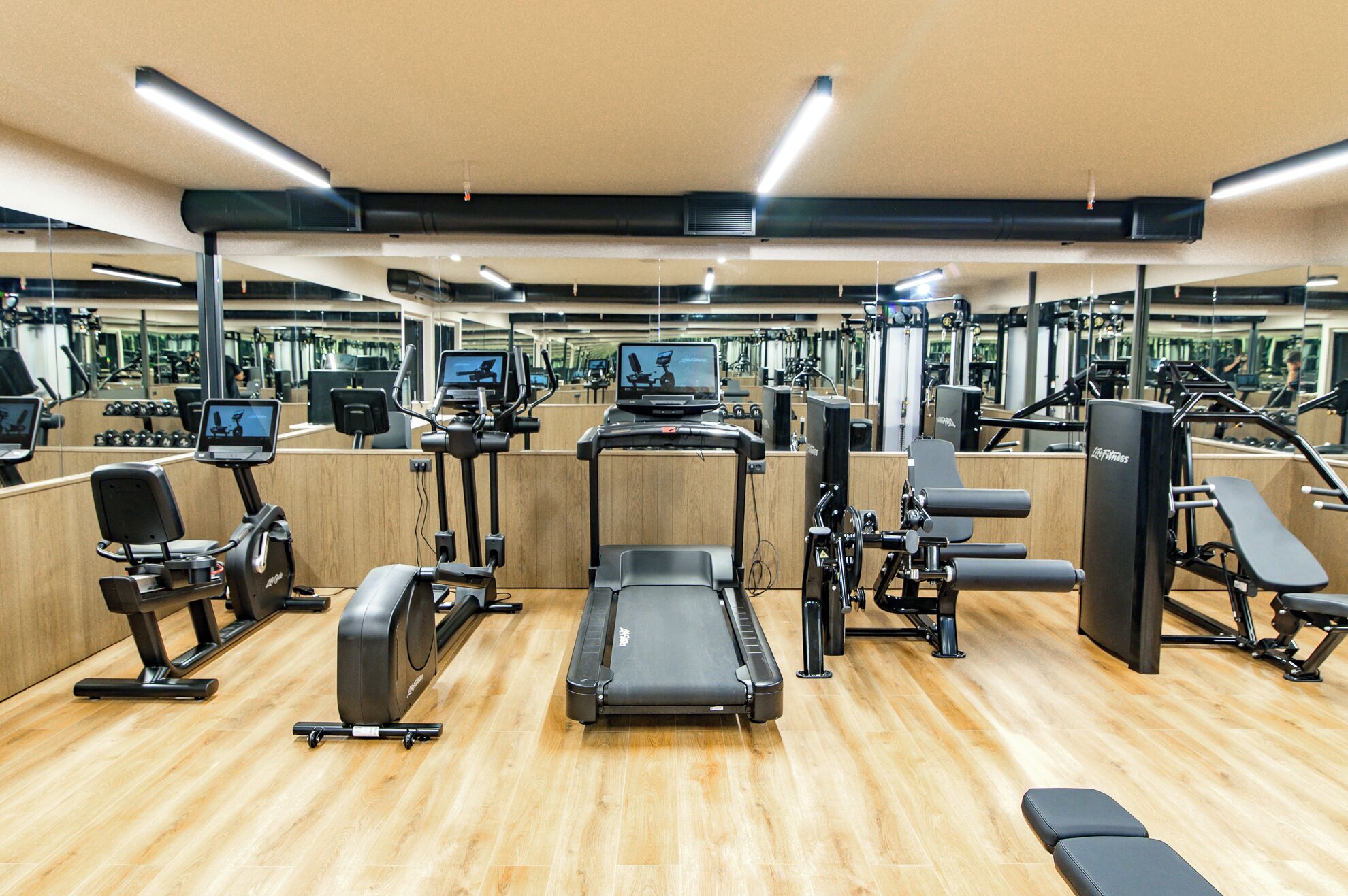 A gym with various exercise equipment, including treadmills, weight machines, and a rowing machine.