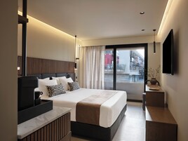 Habitación de hotel moderna con una cama grande, un escritorio y vistas a la ciudad desde el balcón.