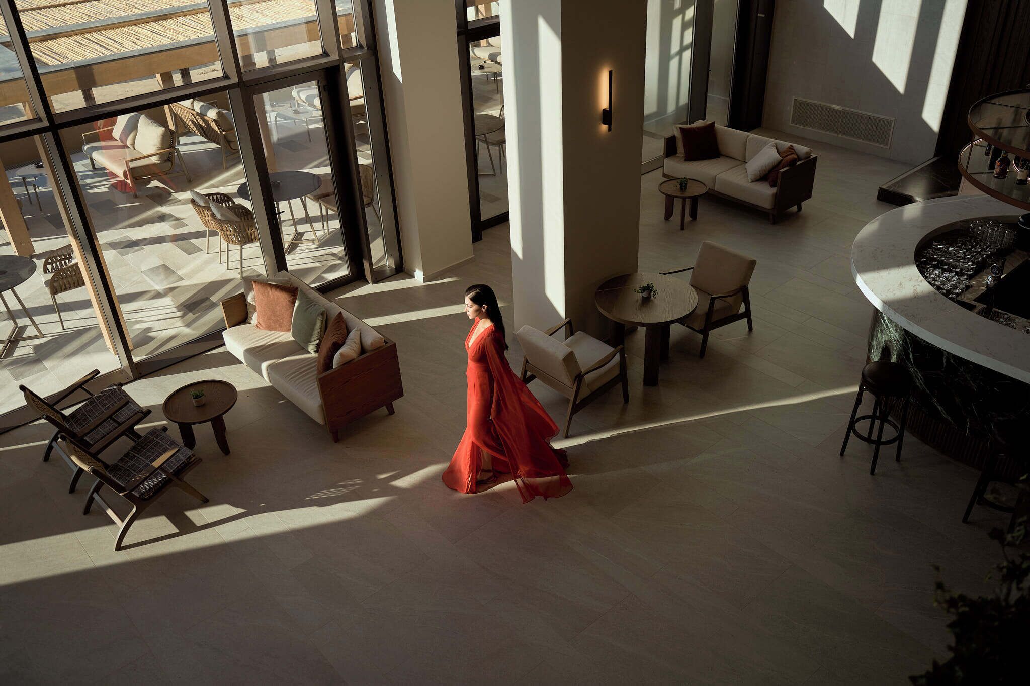 Eine großzügige Hotelhalle mit hoher Decke, großen Fenstern und einer zentralen Sitzecke mit Sofas und Sesseln.