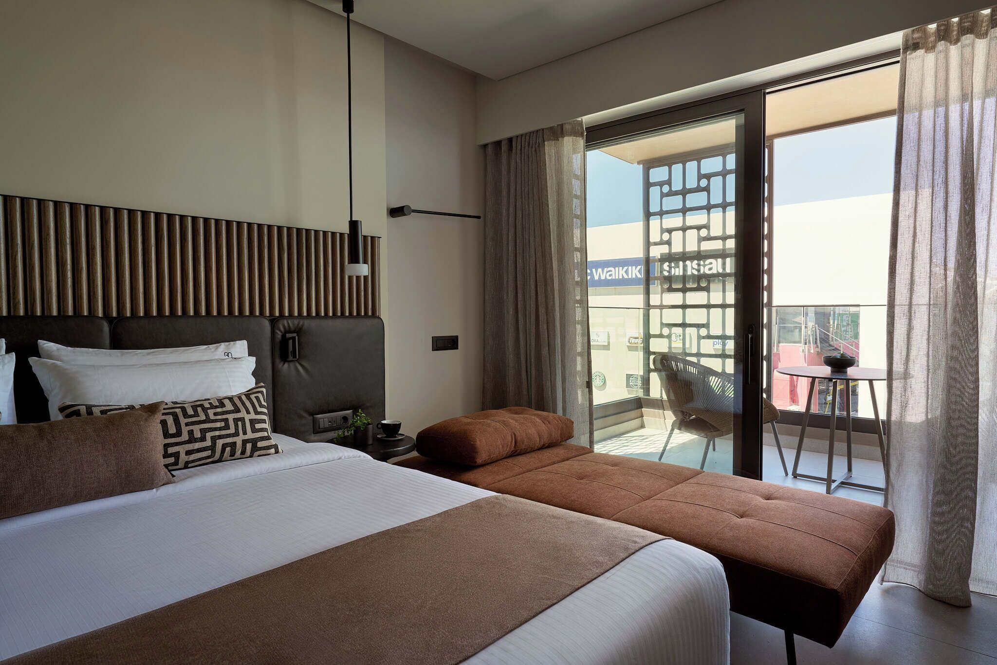 Une chambre d’hôtel moderne dotée d’un grand lit, d’un canapé et d’un balcon offrant une vue sur la ville.