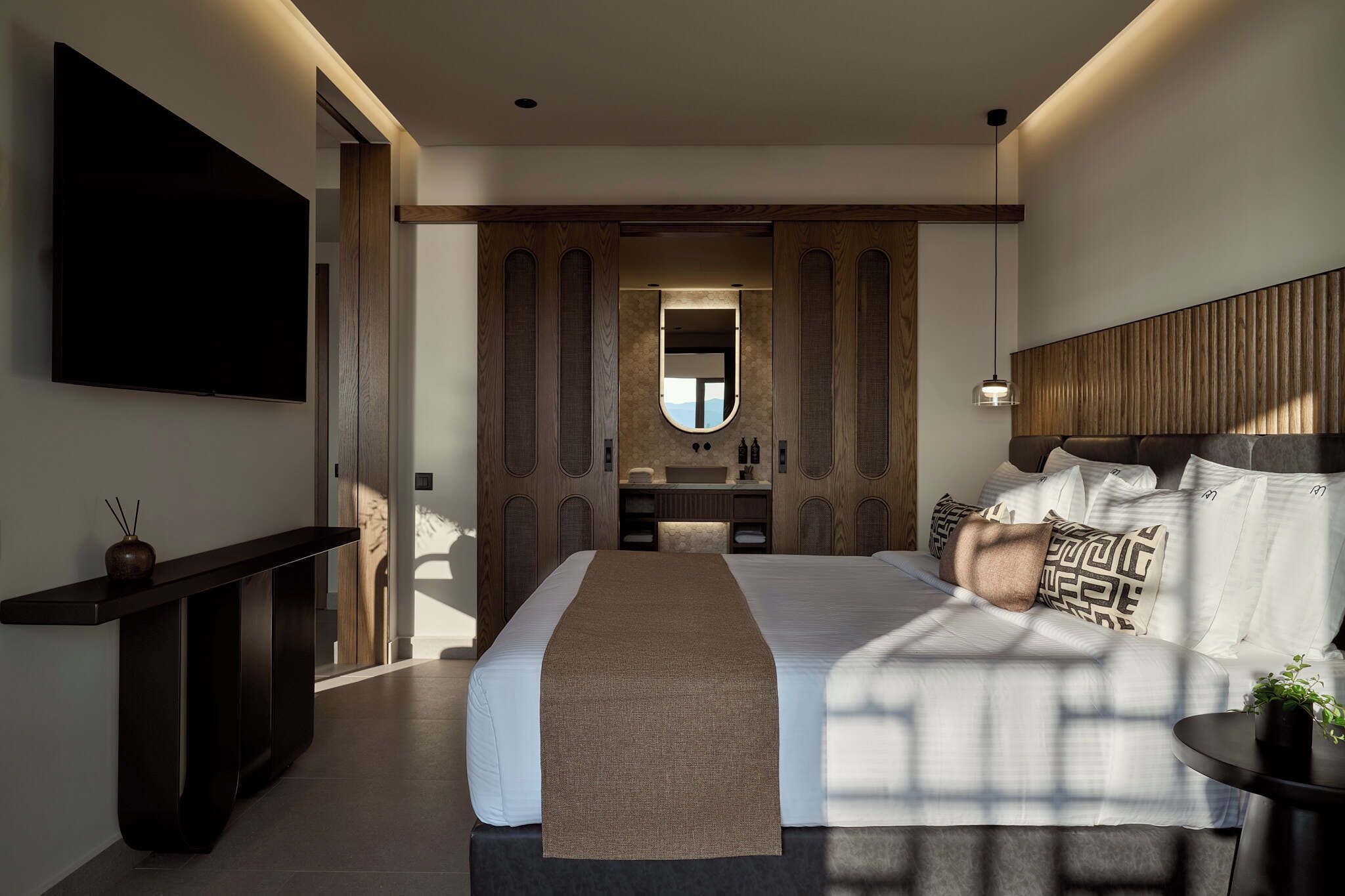 Ein modernes Hotelzimmer mit einem großen Bett, einem Nachttisch, einem Fernseher und einem Spiegel.