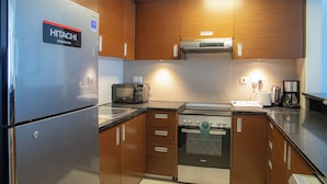 Una cocina moderna con un refrigerador de acero inoxidable, gabinetes de madera, un horno empotrado y un microondas.
