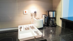 Una cocina con tostadora, cafetera y una bandeja blanca para guardar utensilios.