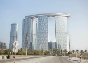 A modern building with a circular design, surrounded by palm trees and a clear sky.