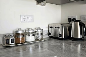 A kitchen with a stainless steel toaster, a kettle, and spice jars on the counter. - House - Sleeps 7 - Parking - Station Close (Preston)