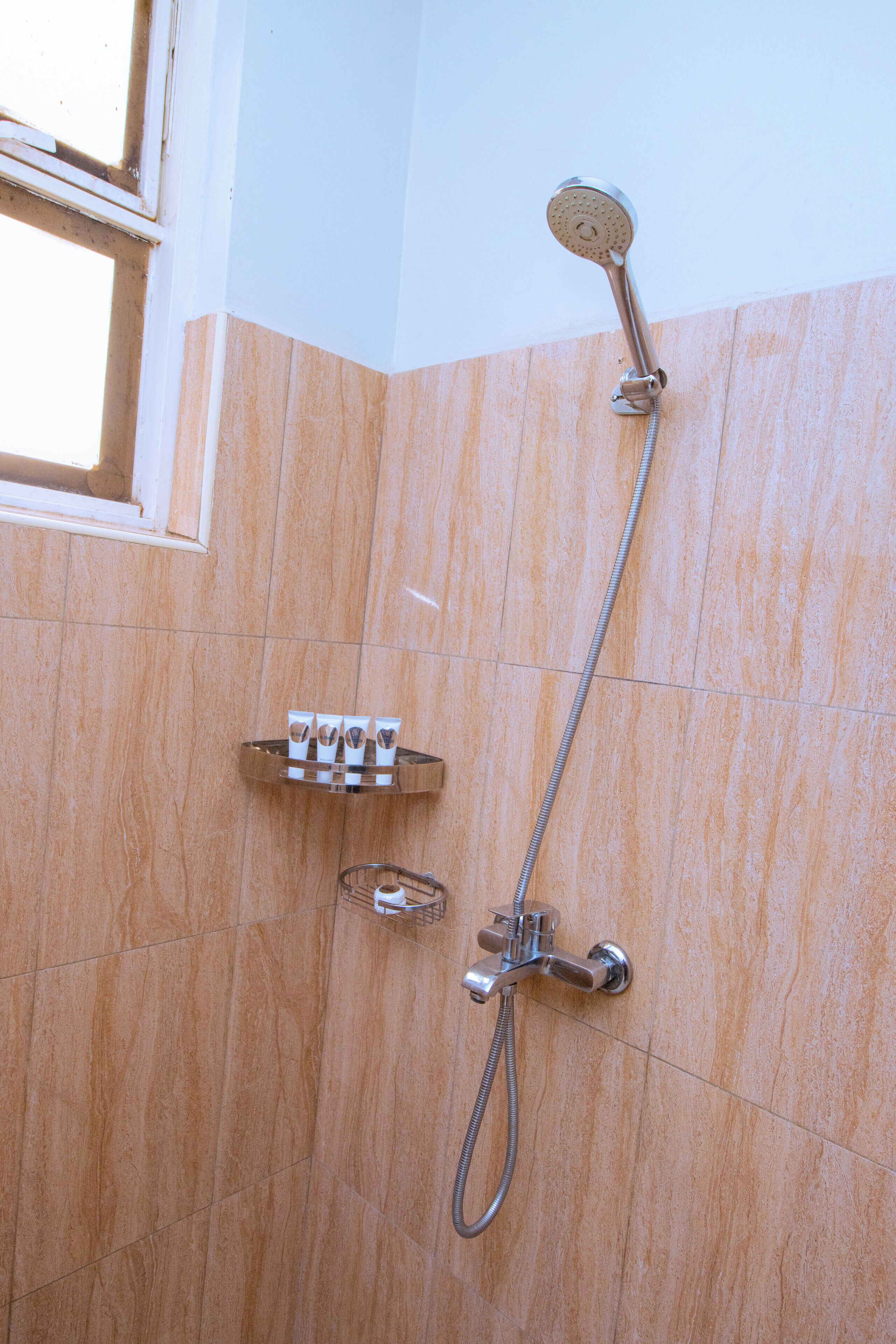 A shower with a handheld showerhead and a wall-mounted faucet.