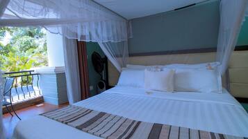 A bed with a canopy, a view of the outdoors, and a chair by the window.