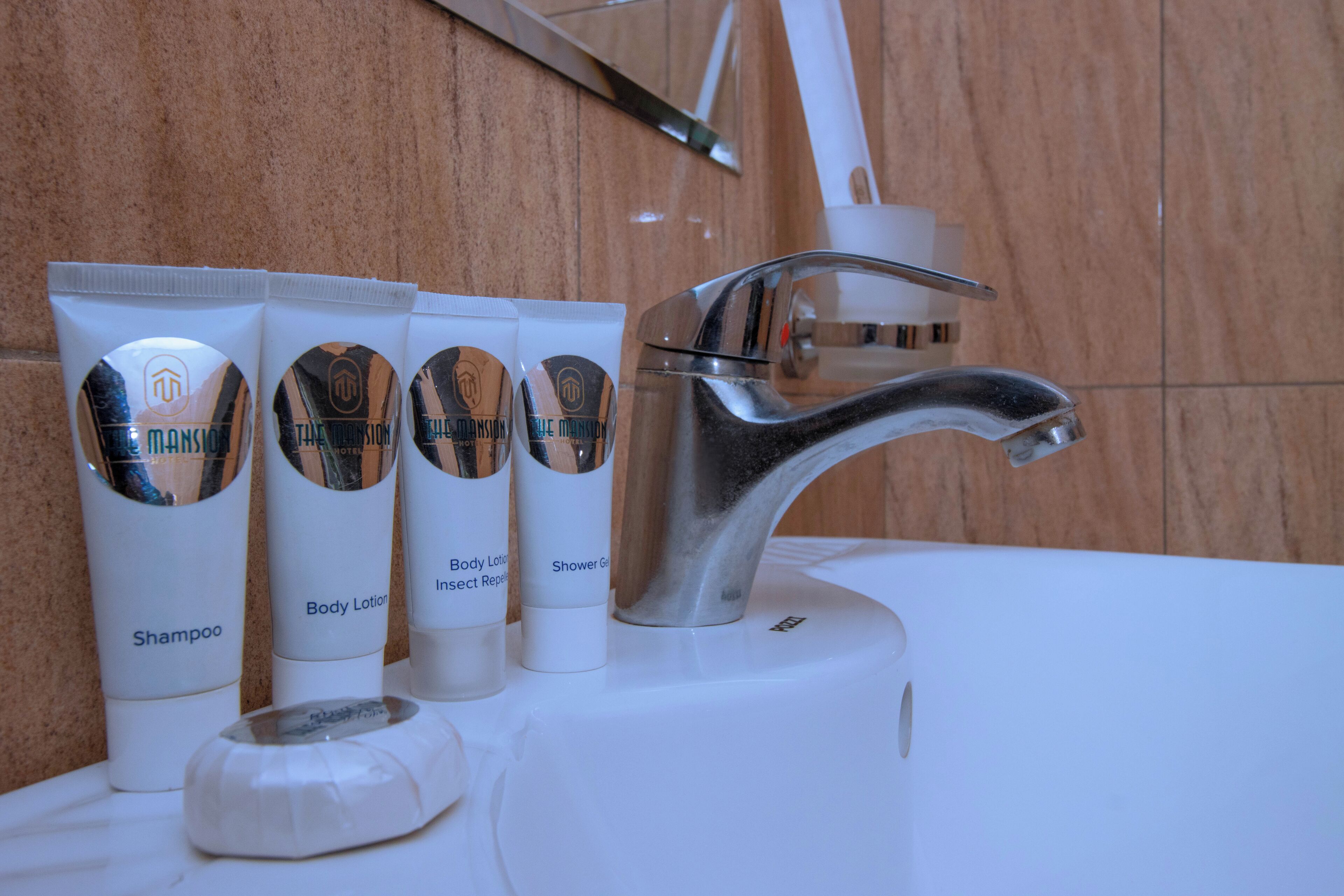 Un lavabo de baño con artículos de aseo, incluyendo champú, loción corporal, repelente de insectos y gel de ducha.